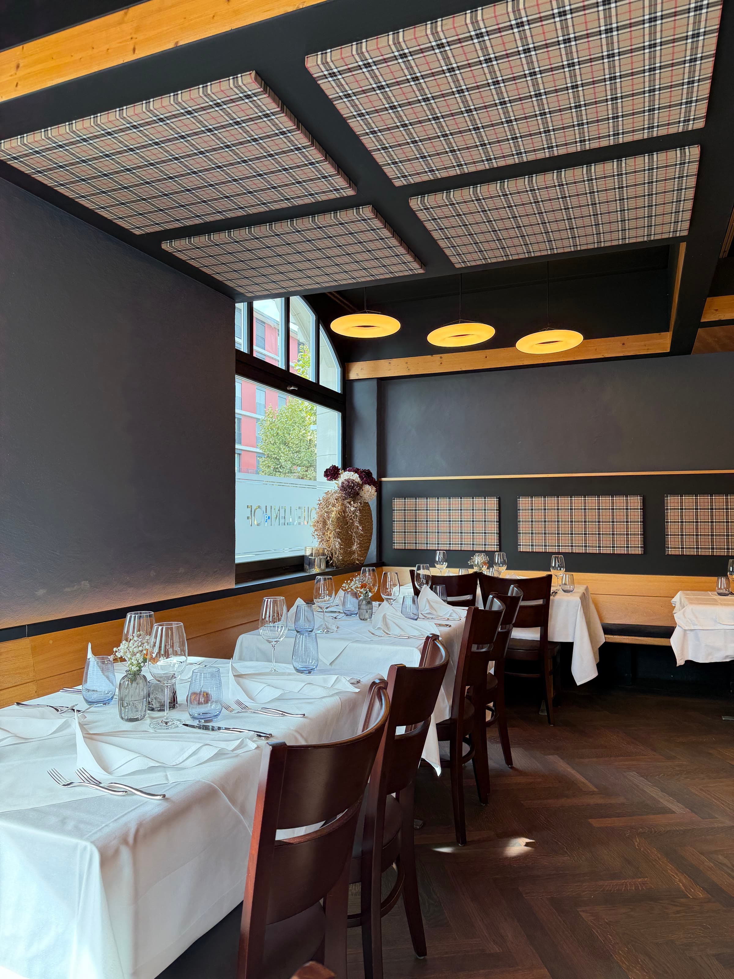 Laid tables under the panelled ceiling, window light across them