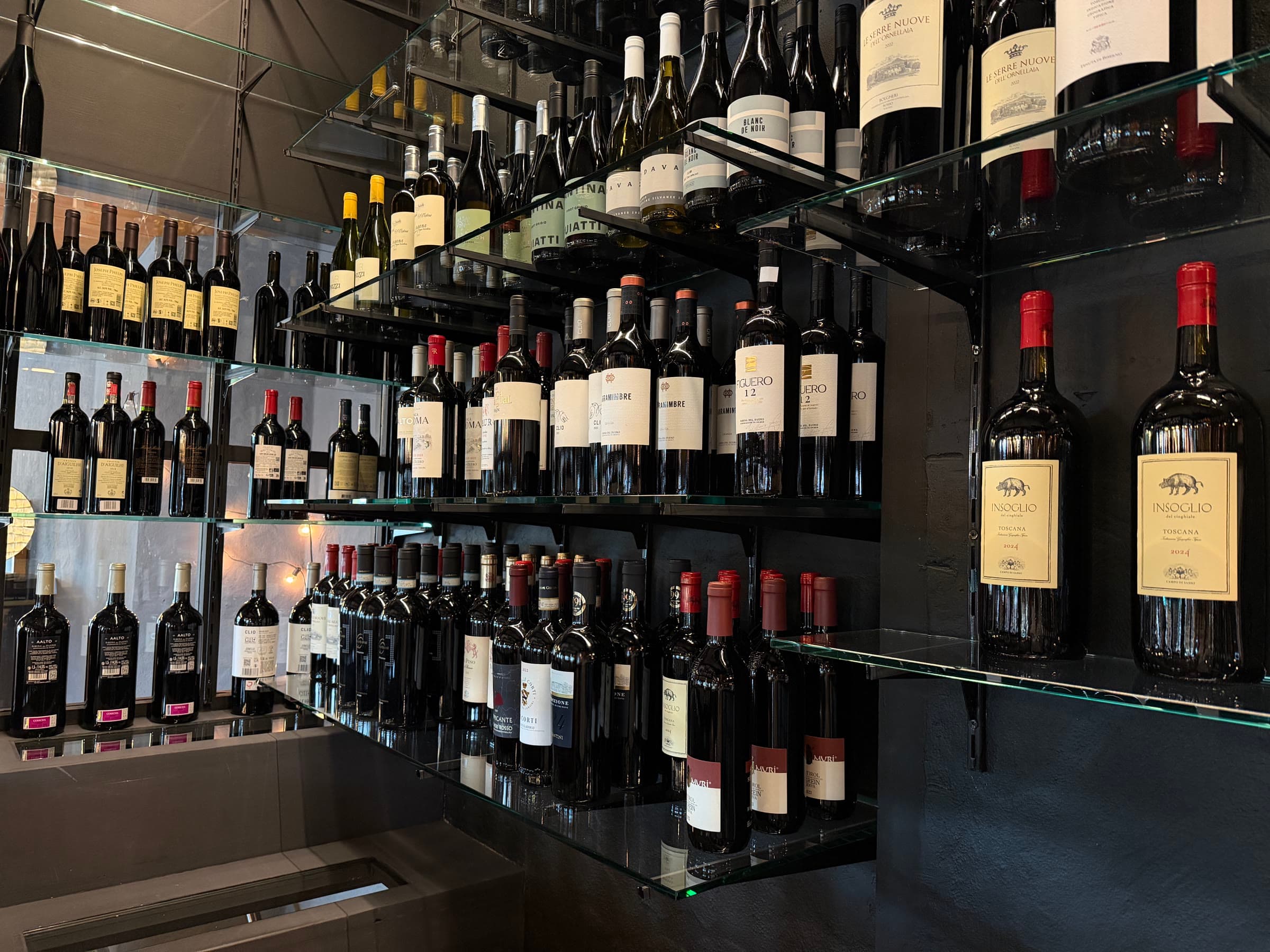 The house's wine wall, bottles on glass shelves