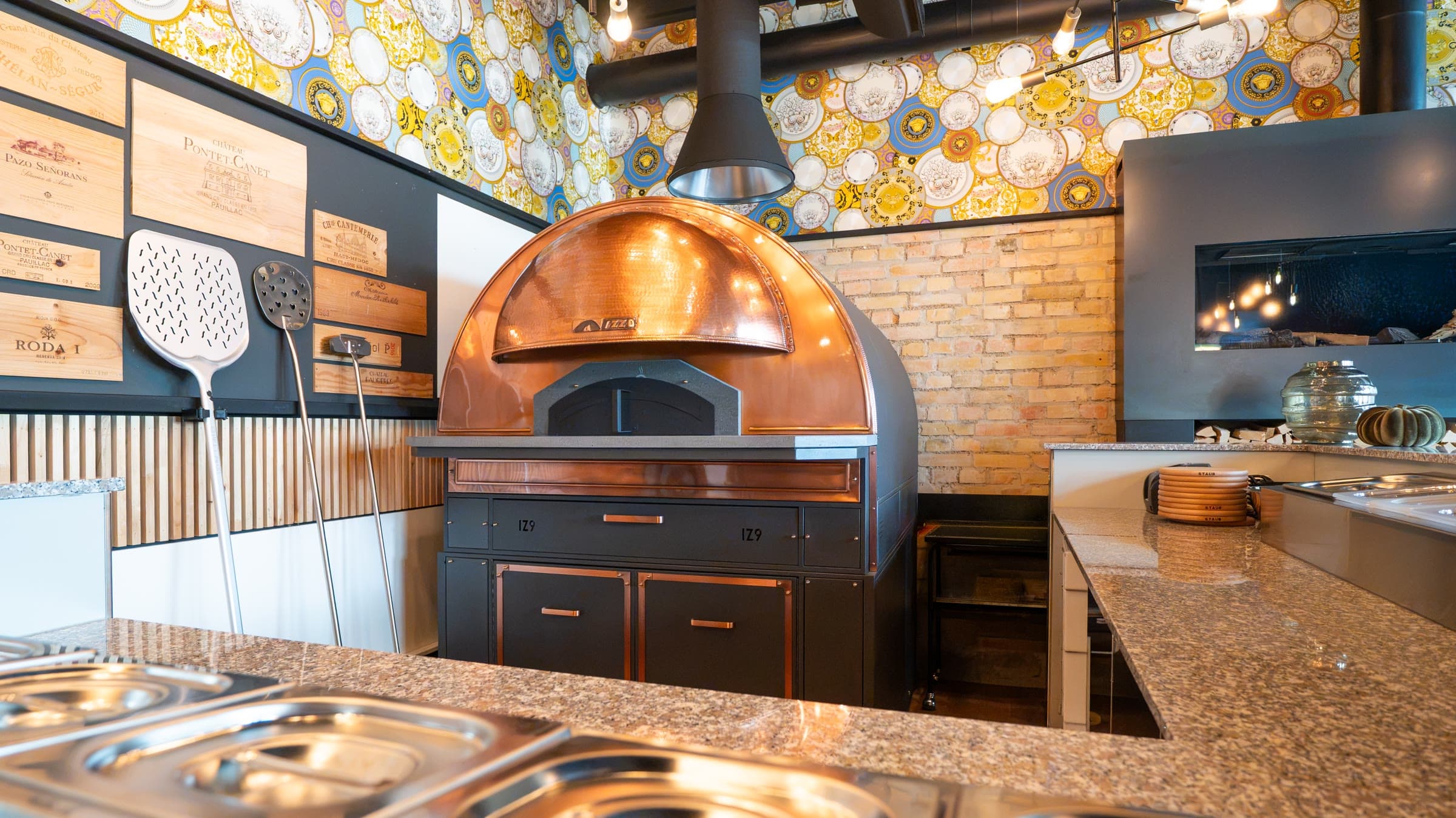 The copper pizza oven at the pass, the peels on the wall beside it