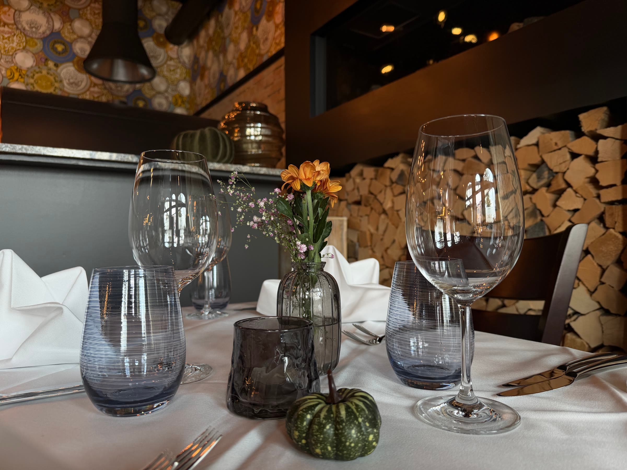 A laid table with glasses and a small vase, the dining room behind it
